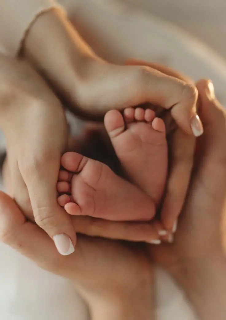 Newborn baby's feet held gently in a parent's cupped hands